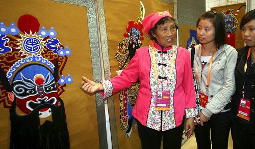 11月1日,參加農(nóng)高會的咸陽市渭城區(qū)70歲老人趙素琴(左一)向參觀者介紹她的臉譜系列刺繡作品。新華社發(fā)(何建虎 攝)