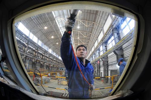 在南車株機(jī)公司車間內(nèi),一名工人正在為機(jī)車頭安裝玻璃(1月18日攝)。新華社記者李尕?cái)z