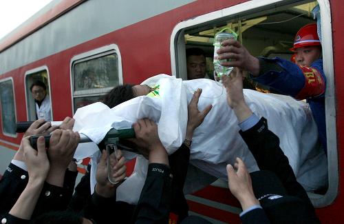 4月6日,一名較危重病人通過車窗被抬進火車車廂。當日早晨,王家?guī)X礦難60名較危重病人,在山西河津火車站被護送上鐵道部安排的專列轉(zhuǎn)診太原。當日,王家?guī)X礦“3·28”透水事故進入第10天,已找到6名遇難工人的遺體,千余名救援人員仍然在全力搜救王家?guī)X煤礦32名被困工人。新華社發(fā)(薛俊 攝)