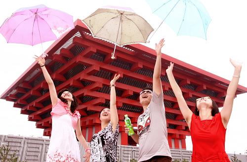 7月17日,一場短暫的小陣雨過后,來自福建和上海的四位游客在世博園把雨傘拋向空中。新華社記者 侯俊 攝