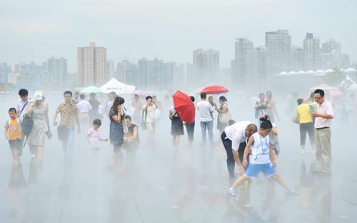 7月17日,“出梅”第一天的上海依然高溫,游客們在世博園慶典廣場釋放的水霧中嬉戲。新華社記者 楊光 攝