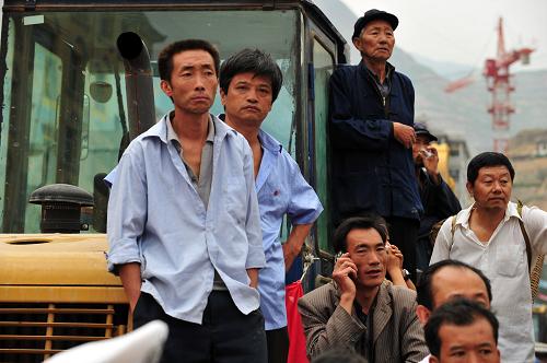 8月28日,在舟曲縣城東出口一小廣場,蹲在一輛工程施工車上的嚴(yán)占海(左三)在給女兒打電話,叮囑身患感冒的女兒注意安全和按時服藥。嚴(yán)占海的女兒是高三年級學(xué)生,以前連縣城都沒出過,這是她第一次走那么遠(yuǎn)的路途。 當(dāng)日,舟曲災(zāi)區(qū)高中異地辦學(xué)首批1000余名師生啟程,前往蘭州進(jìn)行新學(xué)期的教學(xué)、學(xué)習(xí)和生活。特大山洪泥石流災(zāi)害摧毀和淹沒了舟曲縣城兩所小學(xué),沒有受到破壞的舟曲縣一中高中學(xué)校,騰出校舍提供給兩所小學(xué)辦學(xué),全體高中師生前往蘭州和定西進(jìn)行異地辦學(xué)。據(jù)了解,舟曲一中全部3316名師生將在3天之內(nèi)分3批前往蘭州和定西。 新華社記者 梁強(qiáng) 攝