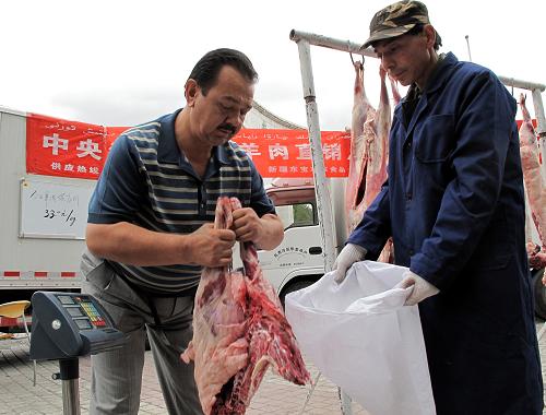 9月3日,一位烏魯木齊市民(左)在購買中央儲(chǔ)備羊肉。新華社記者 賀占軍 攝