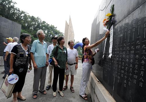 9月3日,抗日航空烈士秦少亭的女兒秦蓉慧(右三)、兒子秦鵬鴻(右五)和秦鵬騫(右四)等親屬在刻有秦少亭名字的紀(jì)念碑前獻(xiàn)花憑吊。新華社記者孫參攝