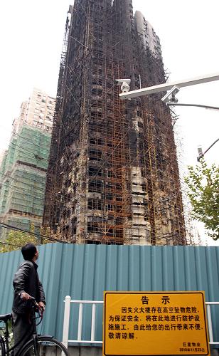 11月24日,一名市民從已封閉管理的上海“11·15”特別重大火災(zāi)事發(fā)大樓前經(jīng)過(guò)。 因上海“11·15”特別重大火災(zāi)事發(fā)大樓存在高空墜物危險(xiǎn),有關(guān)部門將在大樓周邊進(jìn)行防護(hù)設(shè)施施工,以保障行人和車輛安全。 新華社發(fā)(劉友平 攝)