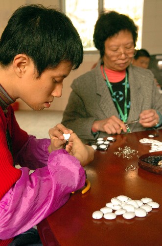 12月3日,一位智障人士(左)和家長一起在廣州德福之家加工出口的手工藝品。 新華社記者 壯錦 攝