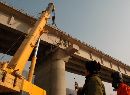 在青海省民和縣境內(nèi),工作人員在指揮架梁機(jī)架梁(12月7日攝)。 新華社發(fā)(張任青子 攝)