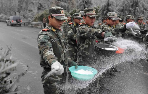1月25日,在通往貴陽機場的貴陽---新寨高速公路上,武警貴陽支隊?wèi)?zhàn)士正在撒鹽。 新華社記者 楊楹 攝