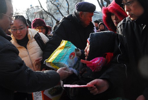 1月26日,一些市民排隊(duì)在煙臺市解放路一處糧油免費(fèi)發(fā)放點(diǎn)領(lǐng)取過年物資。 新華社發(fā)(申吉忠 攝)