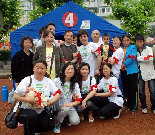 5月22日,在成都市青羊區(qū)西郊體育館災(zāi)民安置點,心理咨詢師和災(zāi)區(qū)群眾、志愿者合影。 新華社發(fā)(李佳明 攝)