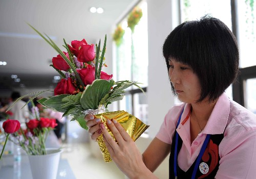 7月25日,一名花卉專業(yè)志愿者在制作北京奧運會和殘奧會頒獎花束。當日,名為“紅紅火火”的北京奧運會和殘奧會的頒獎花束在北京奧運花卉配送中心首次向中外媒體亮相。頒獎花束整體呈尖塔狀,高40厘米,胸徑25厘米,由主花材月季和火龍珠、假龍頭、書帶草、玉簪葉和芒葉等配花配葉組成?;ㄊ暮Y(jié)以中國絲綢為材,采用傳統(tǒng)中國結(jié)的樣式制作而成,絲帶上印有北京奧運會會徽。 北京奧運會和殘奧會期間,將有6000束頒獎花束展現(xiàn)在奧運會和殘奧會的頒獎臺上。 新華社記者羅曉光攝