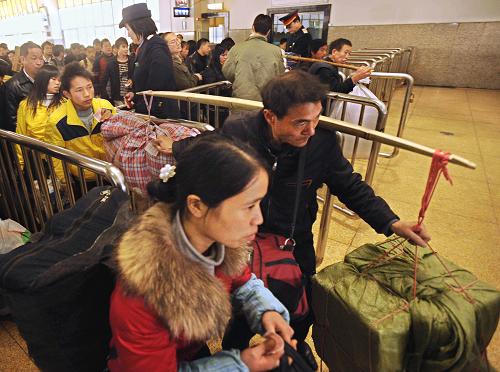 12月7日,兩位外來務(wù)工人員攜帶行李通過杭州火車站檢票口。 新華社記者 譚進(jìn) 攝