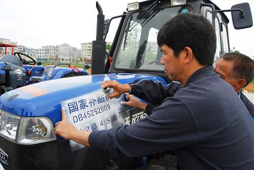 4月24日,在靖西縣2009年農(nóng)機購置補貼機具發(fā)放儀式上,一位工作人員對國家補貼農(nóng)機進(jìn)行編號。 新華社發(fā)(趙京武 攝)