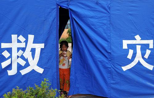7月11日,在云南姚安地震的重災(zāi)區(qū)官屯鄉(xiāng)官屯村,一名小女孩在搭好的帳篷門口喝水。 新華社記者 藺以光 攝