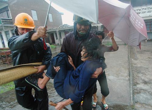 8月9日,浙江溫嶺市濱海鎮(zhèn)村干部冒著暴風雨轉(zhuǎn)移行動不便的老人。新華社發(fā)(鄭玲富 攝)