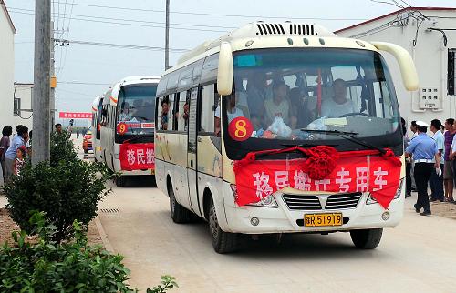 8月16日,載著移民的大客車駛?cè)爰I移民新村。 新華社記者 王頌 攝