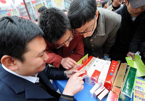 3月14日,煙草管理部門的專業(yè)人員(左一)向消費者傳授識別假煙的技巧。當日,江蘇省暨南京市工商、質(zhì)監(jiān)、消協(xié)、企業(yè)代表、行業(yè)協(xié)會等相關(guān)部門在南京新街口正洪街廣場聯(lián)合舉行紀念3·15國際消費者權(quán)益日活動。 新華社記者 孫參 攝