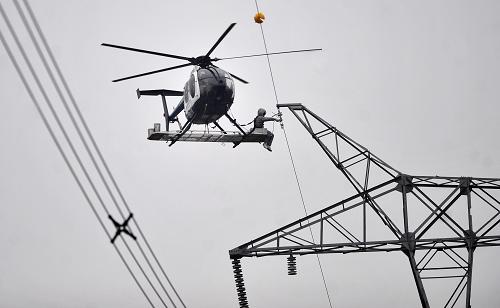 4月12日,檢修人員在超高壓輸電線路上進(jìn)行直升機(jī)帶電作業(yè)。新華社記者 郝同前 攝