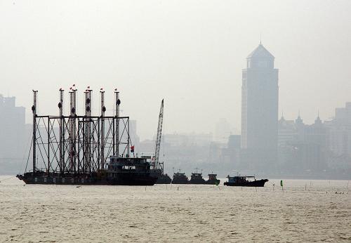 在鄰近珠海九洲港的海面上,施工人員在建設(shè)港珠澳大橋珠澳口岸人工島(2010年8月6日攝)。新華社發(fā)(席湖 攝)