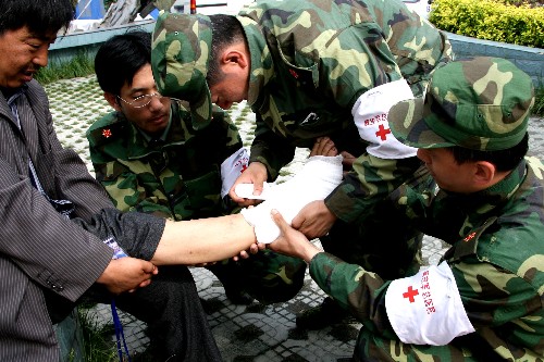 5月18日,中國人民解放軍第301醫(yī)院醫(yī)療隊醫(yī)務(wù)人員在重災(zāi)區(qū)汶川縣映秀鎮(zhèn)為災(zāi)民治療傷病。 新華社特約記者 趙建偉 攝