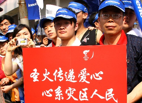5月23日,群眾在火炬?zhèn)鬟f現(xiàn)場(chǎng)手持“圣火傳遞愛(ài)心 心系災(zāi)區(qū)人民”標(biāo)語(yǔ)牌。當(dāng)日,北京奧運(yùn)會(huì)圣火在上海傳遞。 新華社記者陳飛攝