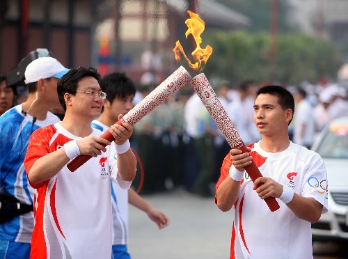 6月14日,火炬手桂陽(yáng)(右)與下一棒火炬手王進(jìn)江交接。當(dāng)日,北京奧運(yùn)火炬?zhèn)鬟f活動(dòng)在貴州省遵義市舉行。 新華社記者邢廣利攝