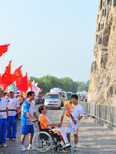 9月4日,火炬手王延朋(右)與下一棒火炬手孫稷交接火炬。當(dāng)日,北京殘奧會(huì)圣火在河南洛陽(yáng)進(jìn)行傳遞。 新華社記者張善臣攝