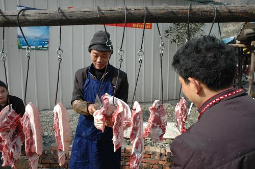 1月21日,在汶川映秀鎮(zhèn)綜合集中安置區(qū)一個用木頭搭起來的鮮肉攤位,店主在出售豬肉。春節(jié)臨近,在“5·12”大地震震中所在地四川汶川縣映秀鎮(zhèn),受災(zāi)群眾正在為過年做準備。板房之間形成的“商業(yè)區(qū)”設(shè)施雖然簡陋,但滿足了受災(zāi)群眾生活基本需求。新華社記者 關(guān)健 攝