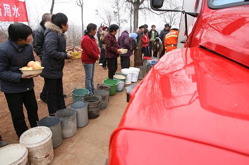 2月18日,在伊川縣呂店鄉(xiāng)蘇溝村,村民在消防車(chē)前排隊(duì)接水。一些村民還準(zhǔn)備了水果、花生等,感謝送水消防官兵。近期,河南省洛陽(yáng)市伊川縣呂店鄉(xiāng)蘇溝村旱情嚴(yán)重,全村140戶(hù)村民面臨飲水困難。伊川縣公安消防大隊(duì)抽調(diào)人員、車(chē)輛為村民送水上門(mén),幫助他們解決飲水問(wèn)題。新華社發(fā)(李書(shū)寶 攝)
