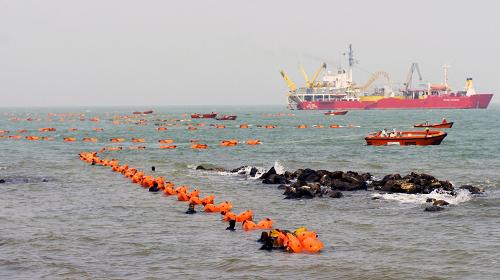 3月17日,工作人員正在把電纜向岸邊牽引。當日15時28分,海南跨海聯(lián)網(wǎng)工程首根海底電纜在海南省澄邁縣橋頭鎮(zhèn)林詩島順利上岸。這根全長32千米、直徑18厘米的超高壓牛皮紙絕緣充油電纜,將使海南電網(wǎng)與南方電網(wǎng)主網(wǎng)連接起來,使海南電網(wǎng)告別孤網(wǎng)運行的歷史。海南聯(lián)網(wǎng)工程于2005年10月經(jīng)國家發(fā)改委正式核準開工建設(shè),總投資近25億元,是中國第一個500千伏超高壓、長距離、大容量的跨海聯(lián)網(wǎng)工程,也是世界上繼加拿大之后第二個同類工程。新華社記者 郭程 攝