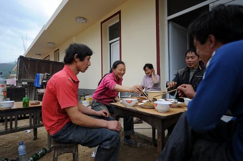 4月21日,文縣碧口鎮(zhèn)聯(lián)豐村村民在新房前吃午飯。截至4月17日,在汶川地震中受災(zāi)嚴(yán)重的甘肅文縣3.4萬戶需要重建新房的農(nóng)戶中,有2.4萬戶受災(zāi)群眾的新房已經(jīng)重建完工,開始遷入新居。新華社記者 聶建江 攝