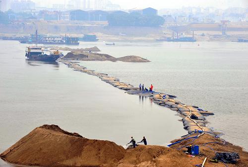 長沙市銀盆嶺大橋附近水域基本完工的湘江壅水圍堰工程現(xiàn)場(chǎng)(10月26日攝)。當(dāng)日,湘江長沙段壅水圍堰工程完工。據(jù)悉,受持續(xù)干旱少雨影響,湘江長沙段近期遭遇嚴(yán)重旱情,為確保沿岸居民用水安全,長沙市啟動(dòng)壅水圍堰工程。該工程首次在湖南水利工程施工中采用“充沙圍堰”技術(shù),即利用高壓泵將細(xì)砂充壓進(jìn)6米長、6米寬、1米高的模袋。潛水員在水下河床固定底座,然后再像堆積木一樣將模袋放置好。整個(gè)壅水圍堰工程完工后,能保證湘江長沙段在400立方米/秒的低枯流量下,達(dá)到25米的安全取水水位。新華社記者 龍弘濤 攝