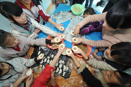 2月7日,志愿者(右上)指導(dǎo)農(nóng)民工子女包餃子。當(dāng)日,在貴州省“意氣風(fēng)發(fā)紅十字會”的流動兒童活動中心內(nèi),10余名農(nóng)民工子弟小學(xué)的學(xué)生在紅十字會志愿者的帶領(lǐng)下,寫春聯(lián)、包餃子,迎接春節(jié)。新華社記者 歐東衢 攝