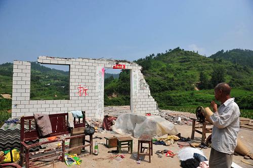 8月9日,湖北省鄖縣柳陂鎮(zhèn)遼瓦村一位老人站在自家即將拆遷完畢的房子前。新華社記者 郝同前 攝