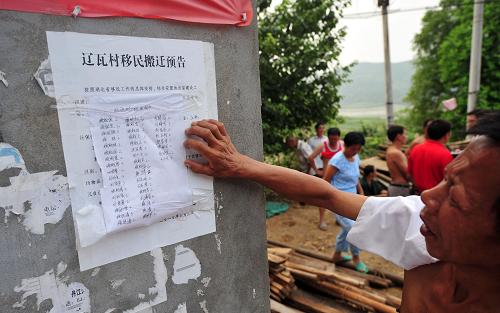 8月9日,湖北省鄖縣柳陂鎮(zhèn)遼瓦村一位村民在觀看關(guān)于移民搬遷的告示。新華社記者 郝同前 攝