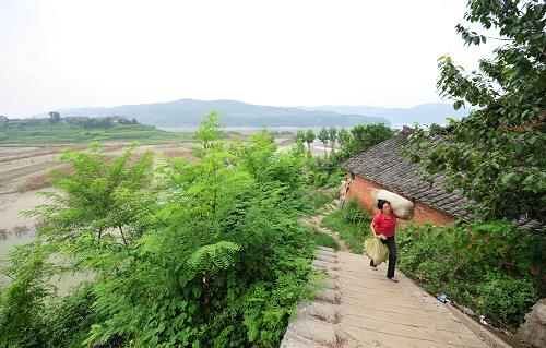 8月9日,湖北省鄖縣柳陂鎮(zhèn)遼瓦村的一位移民將行李運(yùn)到公路邊。他們將于8月11日搬遷到湖北省隨州市。新華社記者 郝同前 攝