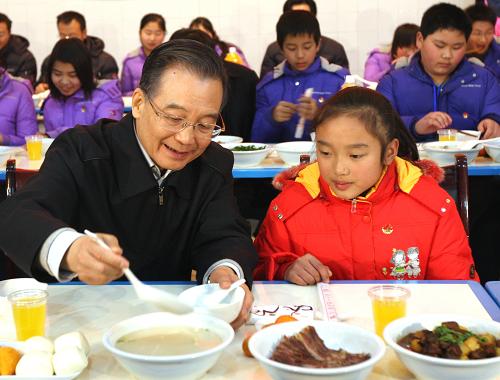 1月24日至25日,中共中央政治局常委、國務(wù)院總理溫家寶來到四川受災(zāi)最為嚴(yán)重的北川、德陽、汶川等地,和災(zāi)區(qū)人民一起過年。這是1月24日,溫家寶在北川中學(xué)食堂與學(xué)生們吃年夜飯時(shí)給身邊的小朱可盛稀飯。新華社記者 姚大偉 攝