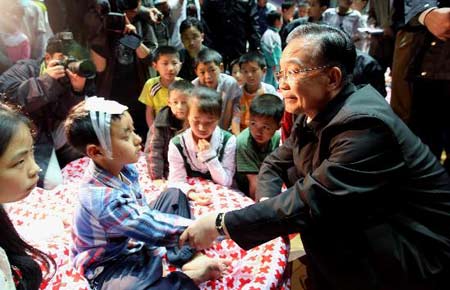 5月13日,溫家寶總理在四川綿陽九州體育館地震災民安置點看望災民。這是溫家寶在安慰受傷兒童。