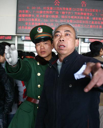 1月28日,一名春運值勤的武警在阜陽站售票廳內為購票旅客服務。新華社發(fā)(盧啟建 攝)