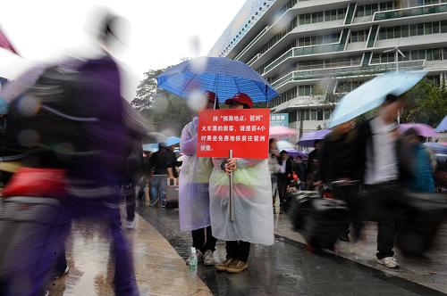 2月7日,志愿者在雨中的廣州火車站廣場為旅客導乘。新華社記者 盧漢欣 攝