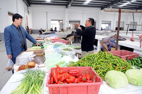一位顧客在江蘇省太倉(cāng)市援建的綿竹市齊天鎮(zhèn)農(nóng)貿(mào)市場(chǎng)買菜(攝于3月24日)。新華社記者陳?ài)茢z