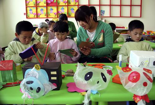 4月20日,山東郯城新愛嬰幼兒園的小朋友在老師的指導(dǎo)下利用廢舊物品制作手工藝品。新華社發(fā)(張春雷 攝)