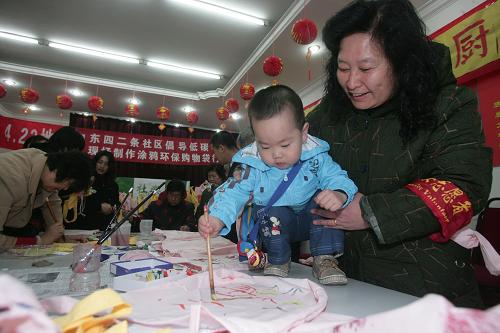 4月22日,在北京市東城區(qū)東四二條社區(qū),一名年齡最小的參與者在環(huán)保袋上涂鴉。新華社發(fā)(郝飛 攝)