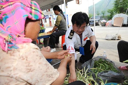 7月4日,在臨時(shí)安置點(diǎn),一名食品衛(wèi)生監(jiān)督人員正在檢查為受災(zāi)群眾午餐準(zhǔn)備的蔬菜。新華社記者 劉續(xù) 攝