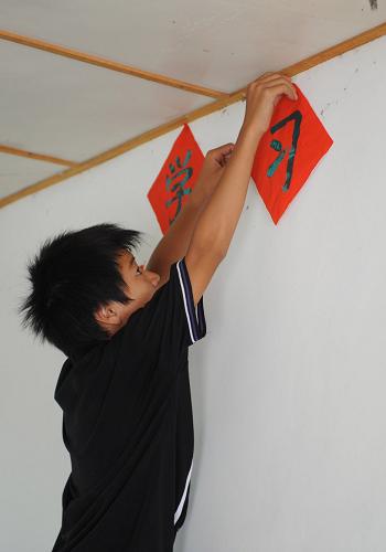 7月4日,一個(gè)男孩子在往墻上貼字。新華社記者 劉續(xù) 攝