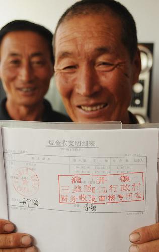 7月24日,在河北省尚義縣滿(mǎn)井鎮(zhèn)三蓋腦包村,村民理財(cái)小組成員謝有忠展示蓋有“五瓣章”的收支明細(xì)表。