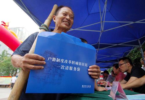8月15日,重慶市江北區(qū)觀音橋步行街,一名外來務(wù)工人員在咨詢點拿取戶籍制度改革的相關(guān)資料。新華社記者 陳誠 攝