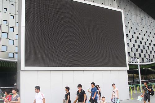 8月15日,參觀者從上海世博園市民廣場大屏幕前經(jīng)過。新華社記者 汪永基 攝