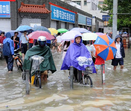 10月8日,市民在積水嚴重的??谑薪诸^行進。新華社記者 王存福 攝