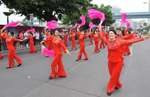5月17日,演員為街道兩旁觀眾表演“紅扇舞”。新華社記者 何俊昌 攝
